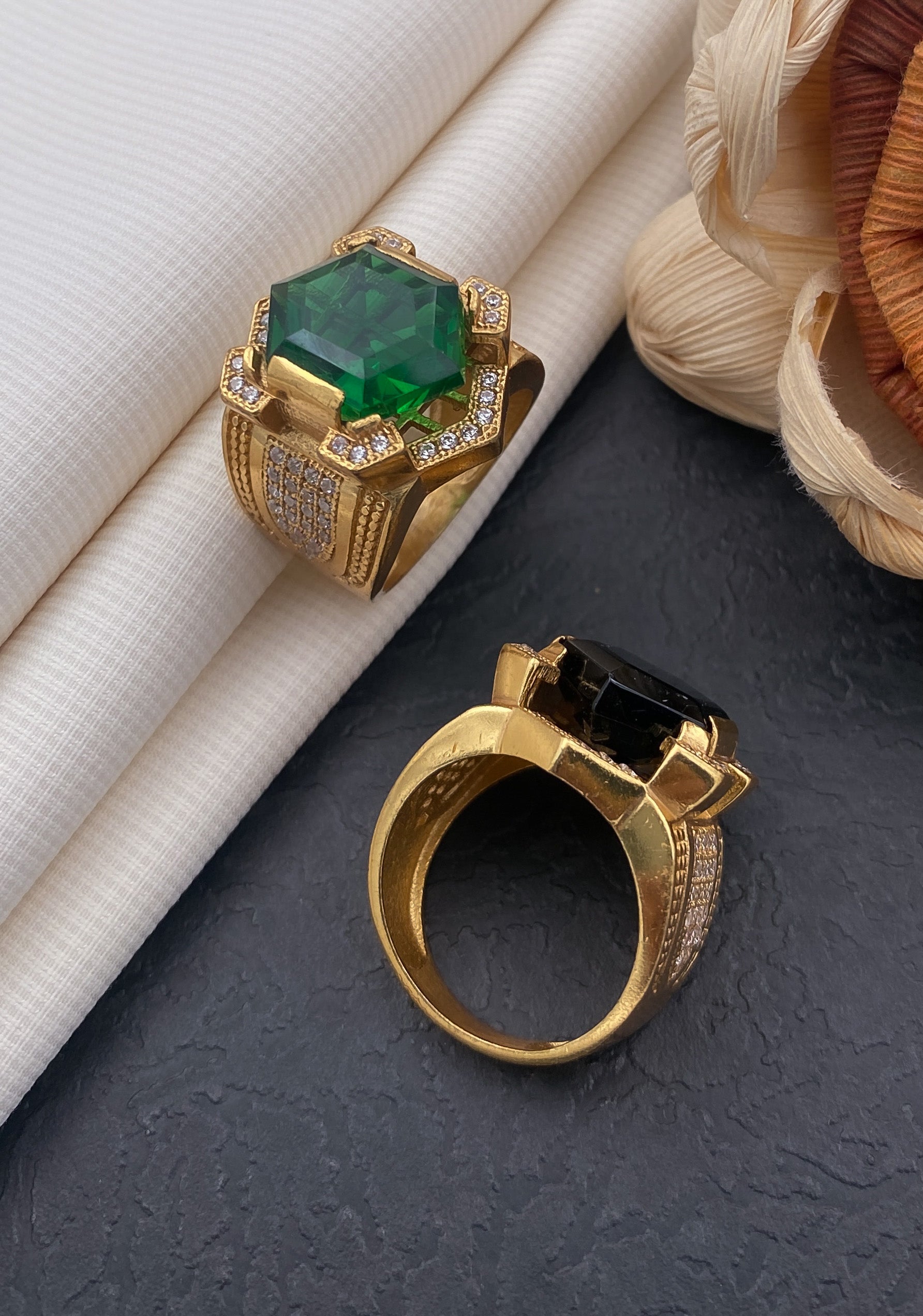 Premium Photo | A green diamond ring with a green stone sits on a black  surface